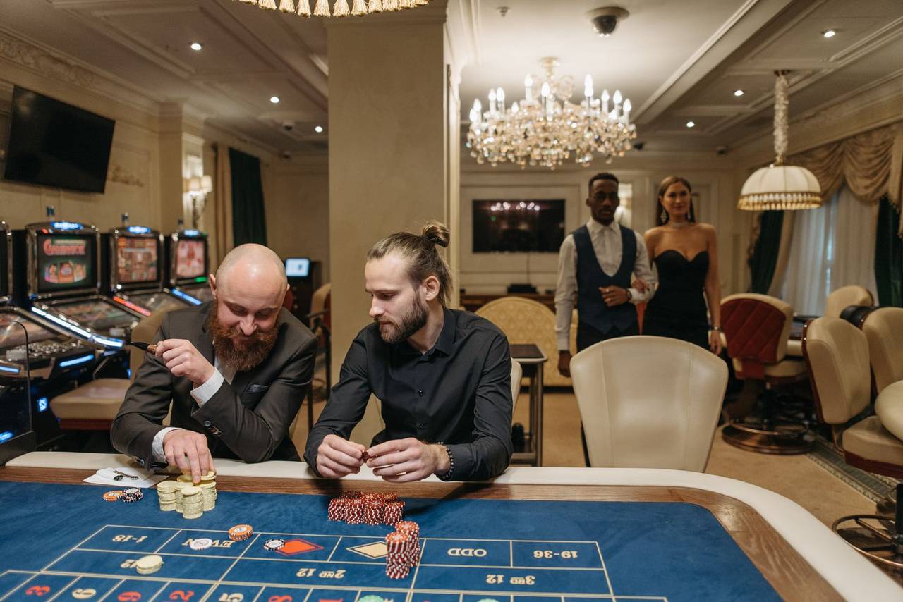 Suasana interior casino dengan pemain di sekitar meja permainan