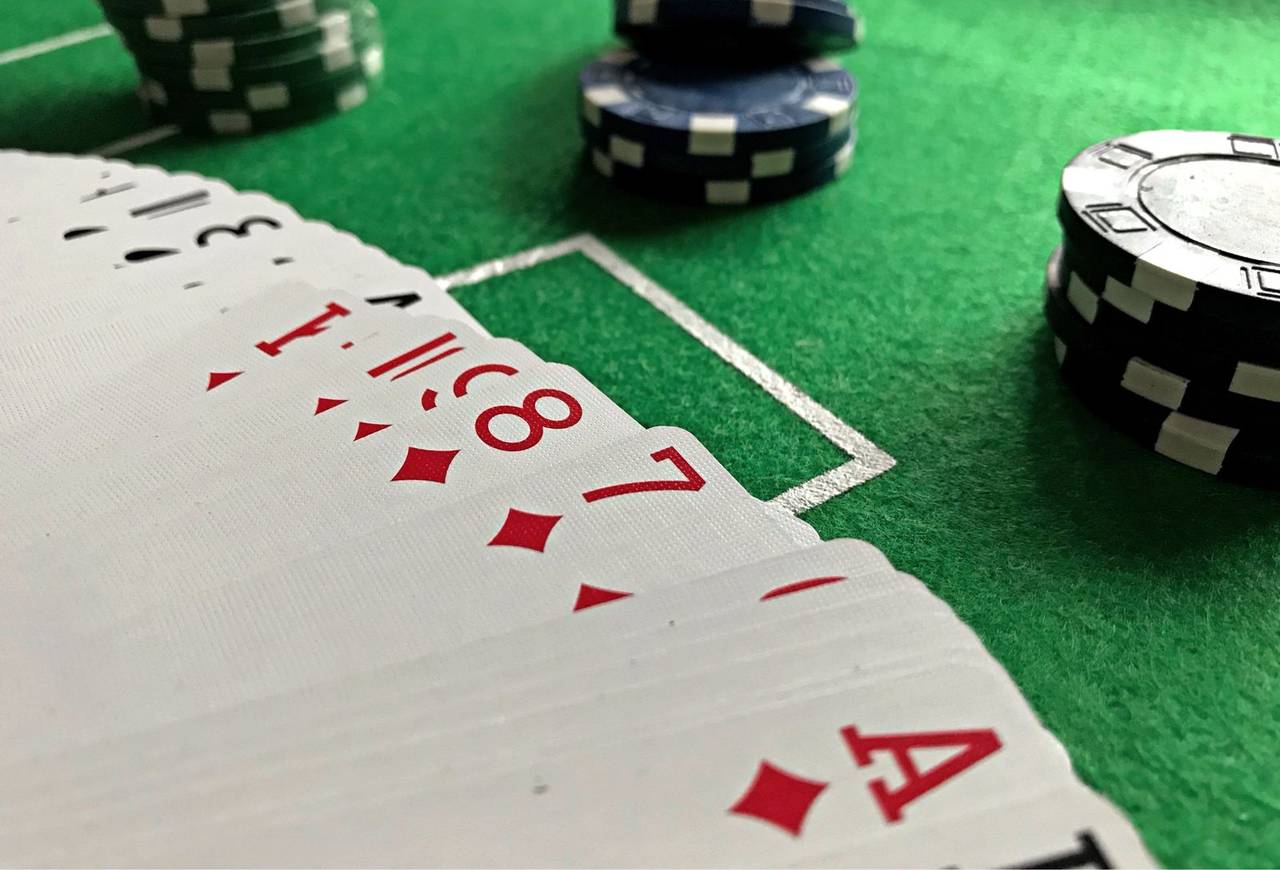 Kartu remi dan tumpukan chip di atas meja hijau